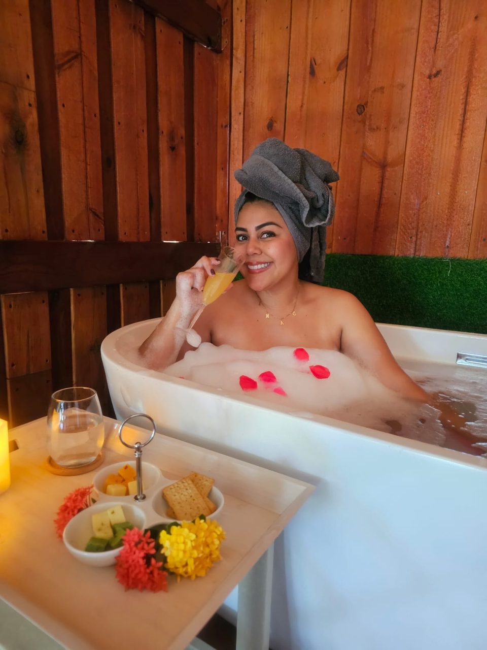 Guest enjoying a petal bath ritual with a tray of fruit and flowers set across the tub.