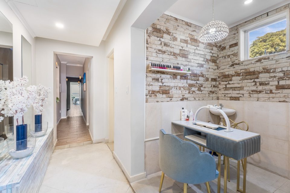 Bright interior corridor with a mirrored vanity station and a reclaimed-wood feature wall leading to the treatment rooms.
