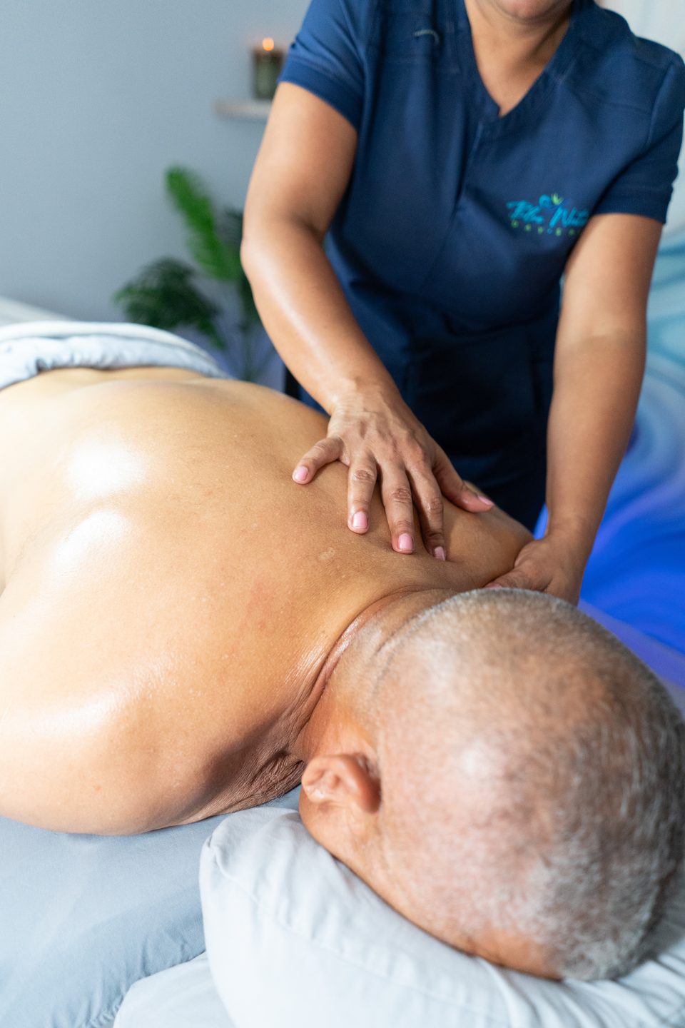 Therapist working across a guest's upper back during a deep tissue massage.