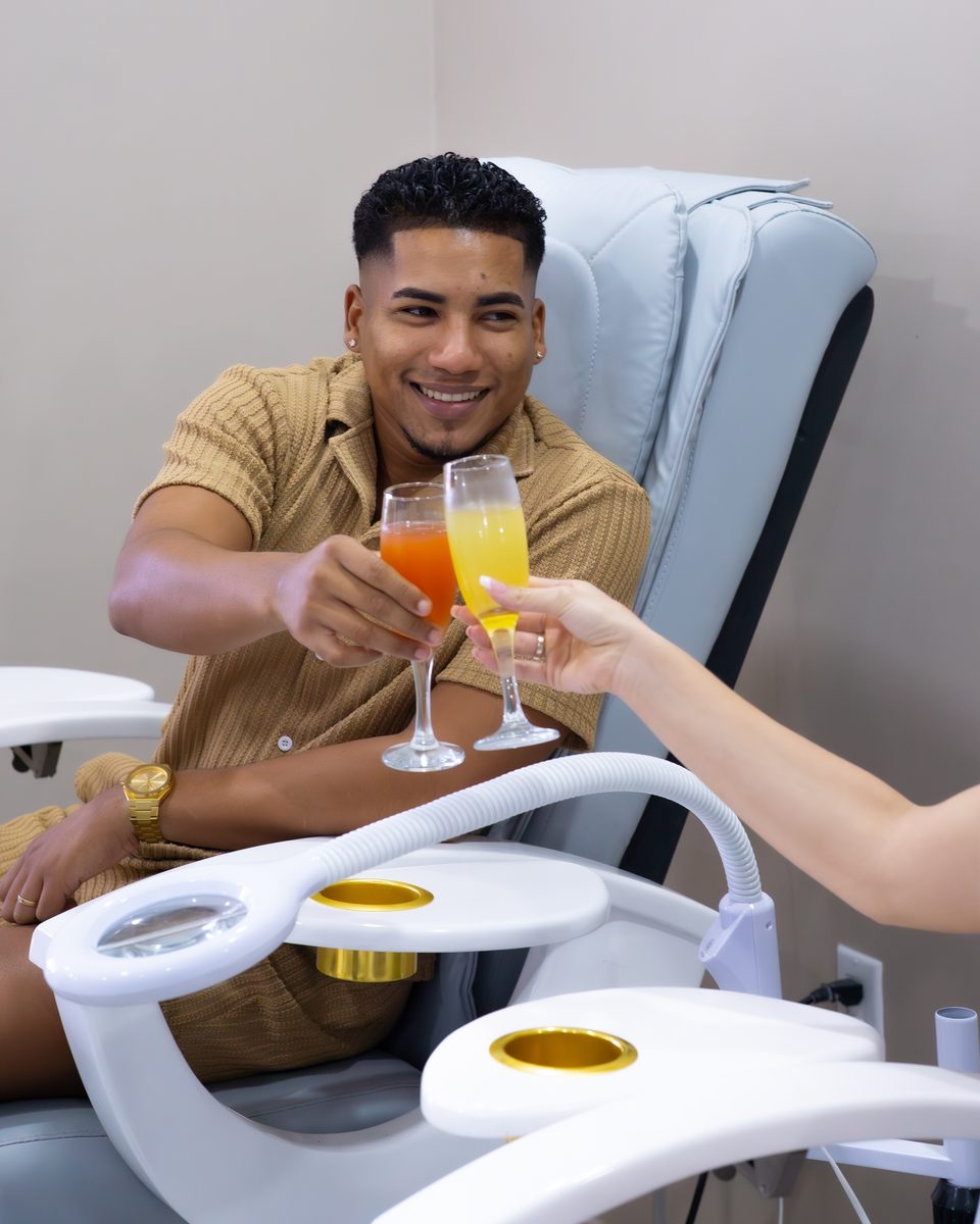Guest relaxing in a treatment chair with a welcome drink in hand.
