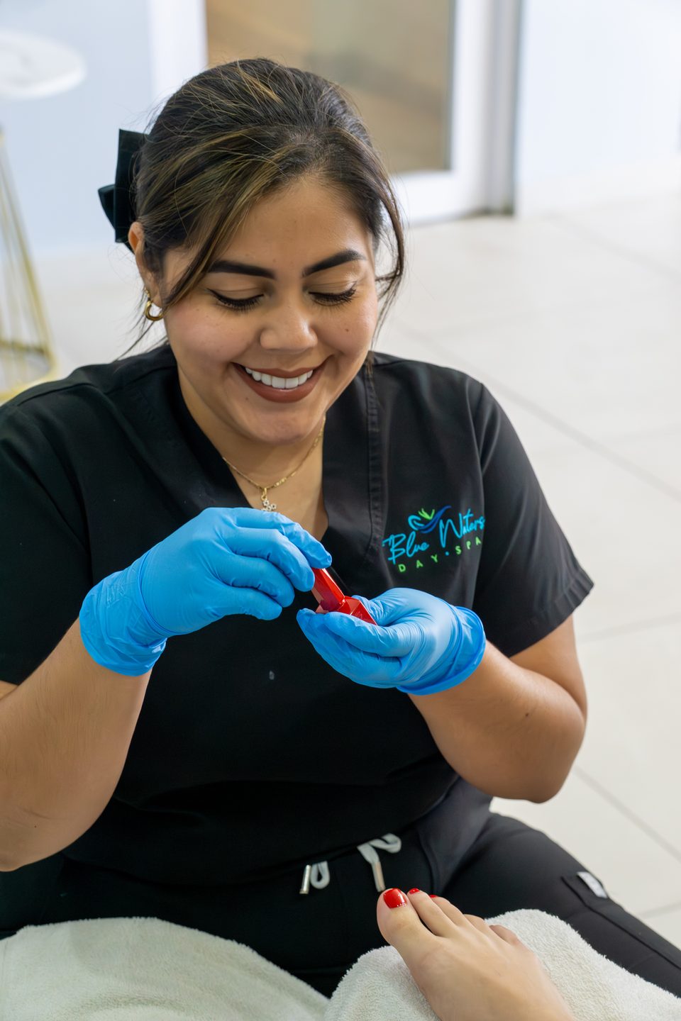 Nail technician painting a guest's nails with a fine brush.