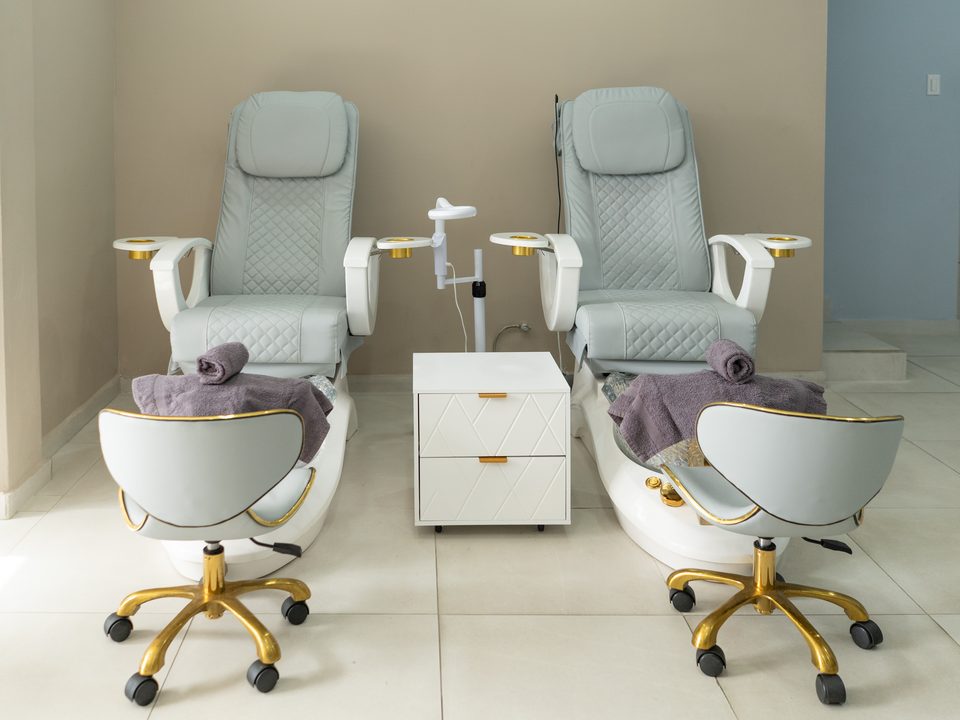 Two pedicure thrones with gold-finished bases and folded towels, ready for guests.