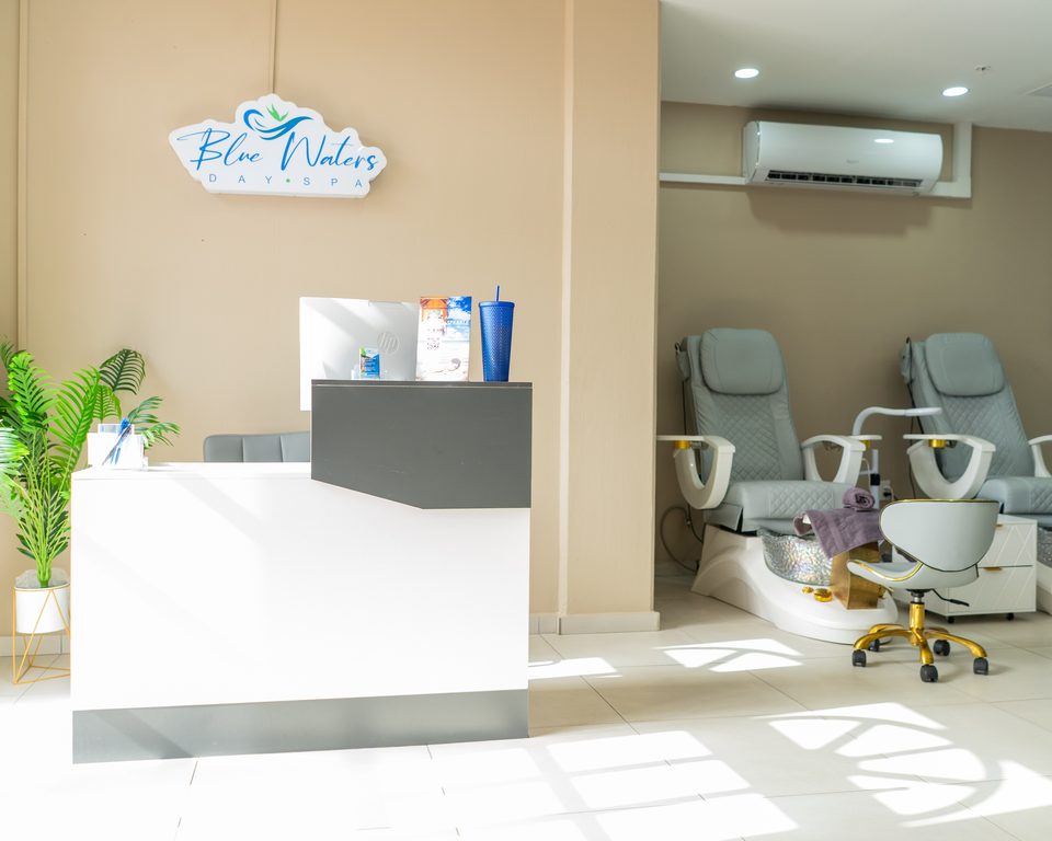 Reception desk in natural daylight with pedicure chairs arranged along the far wall.
