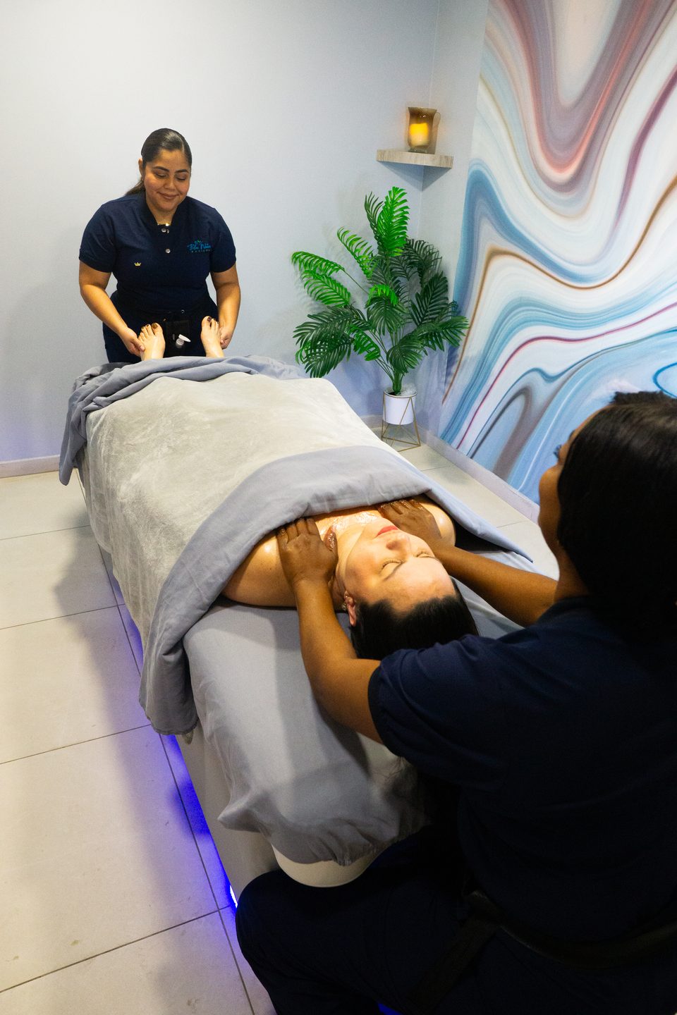 Therapist preparing a treatment in a room with a flowing marbled feature wall.