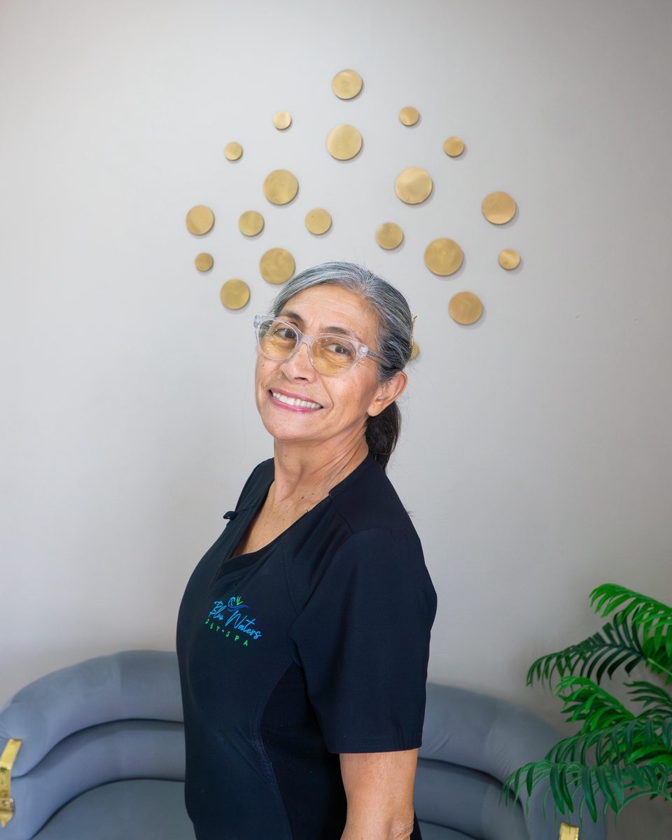 Smiling Blue Waters team member in uniform in front of a gold-accented wall.