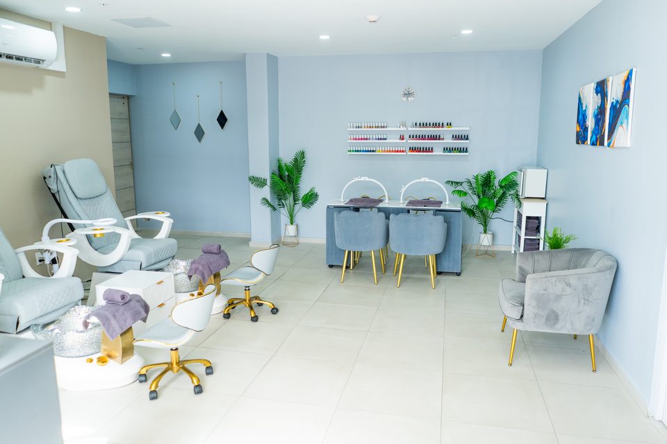 Treatment room in soft blue tones with a reclining spa chair, consultation seating and potted greenery.