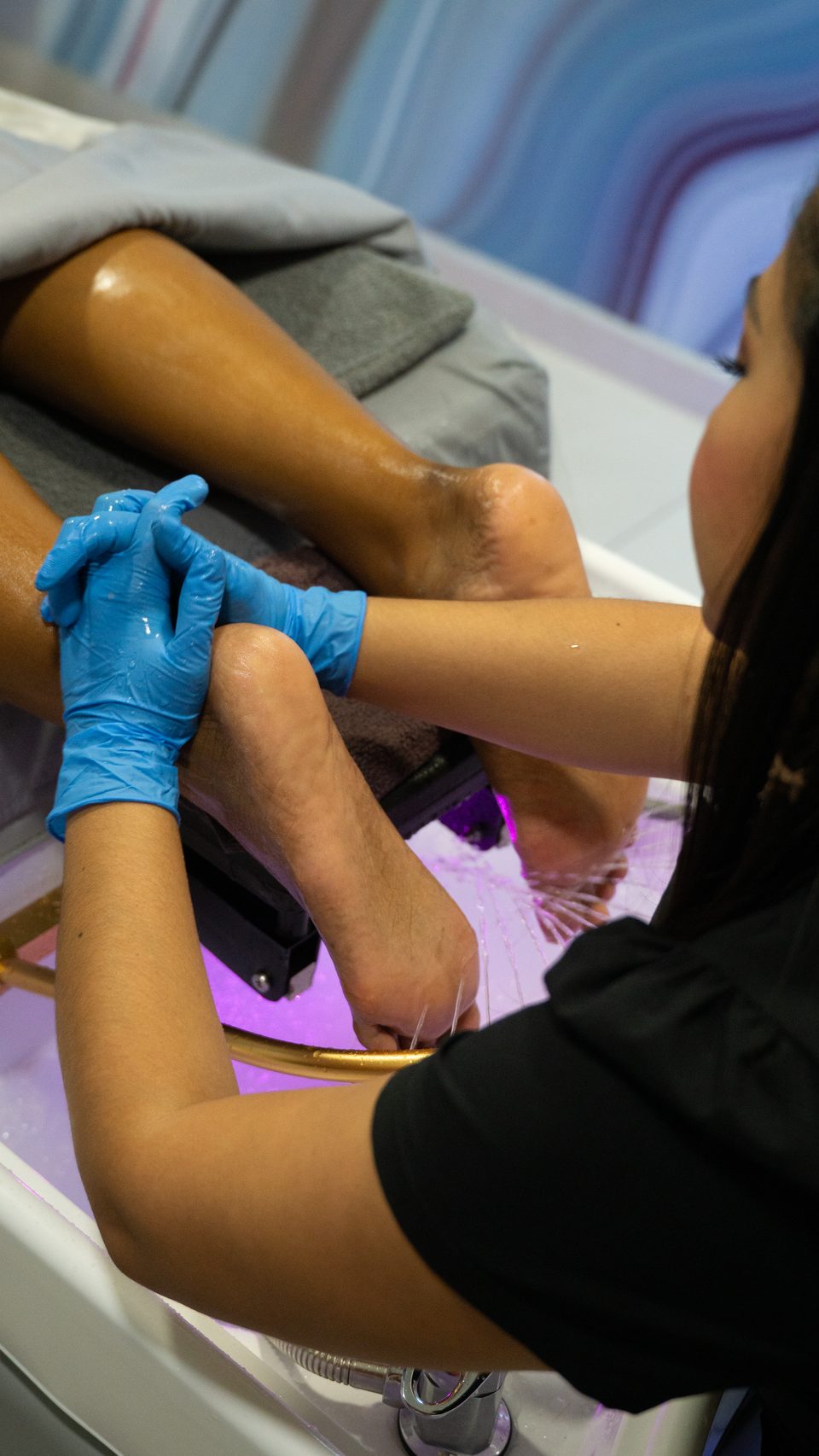 Gloved therapist carrying out a precise waxing treatment.